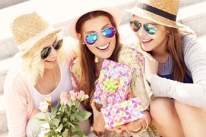 tri mladé ženy sa smejú s darčekom v ruke