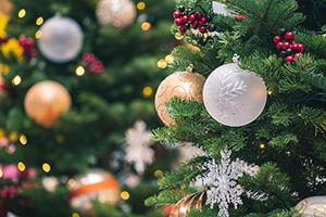 Biele a zlaté vianočné gule zavesené na zelených vetvičkách vianočného stromčeka